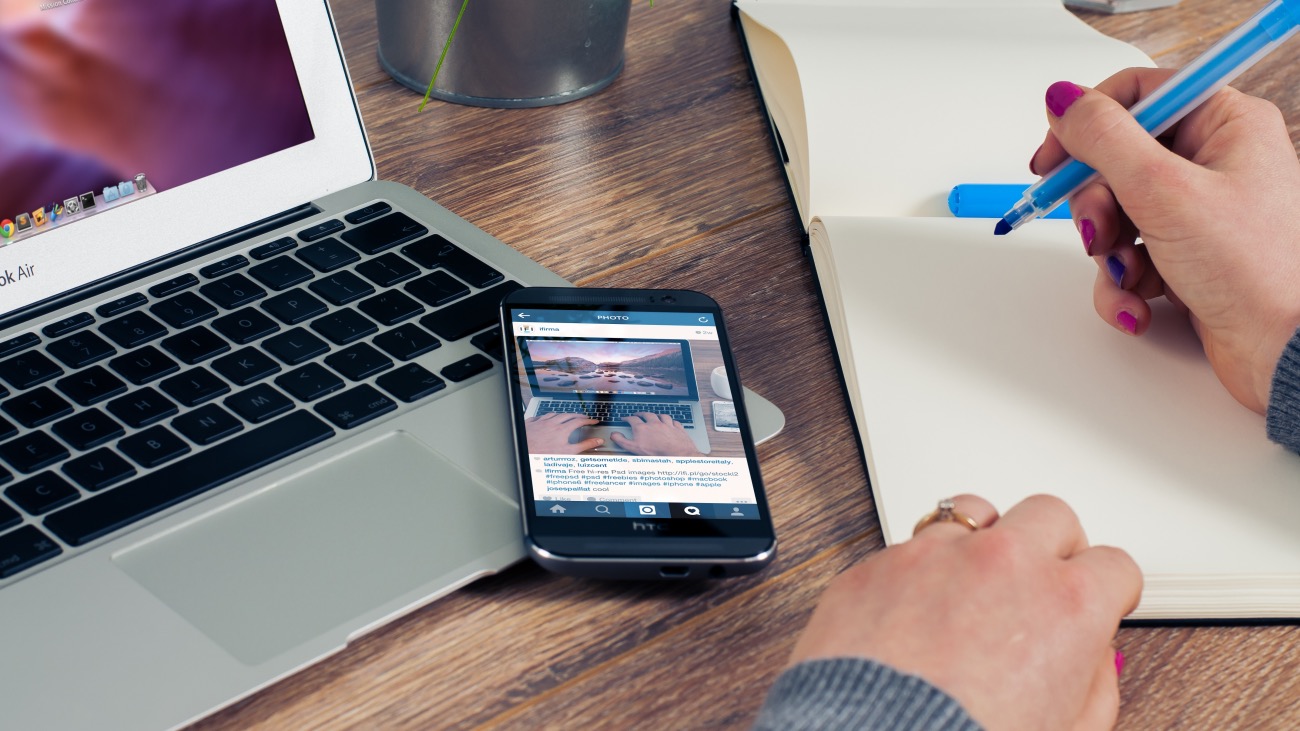 social media displayed on iPhone and woman taking notes